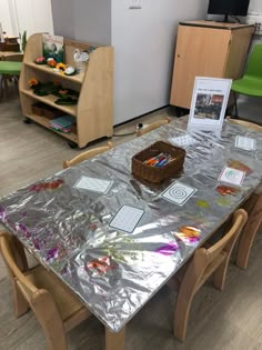 the table is covered with plastic wrap and has flowers on it, along with bookshelves