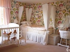 a baby's room decorated in pink and white with hot air balloons on the wall