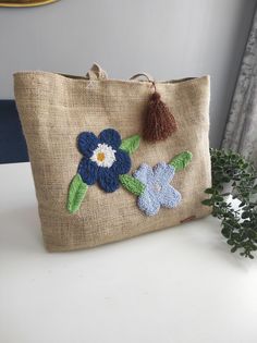 a small bag with flowers on it sitting on a table next to a potted plant