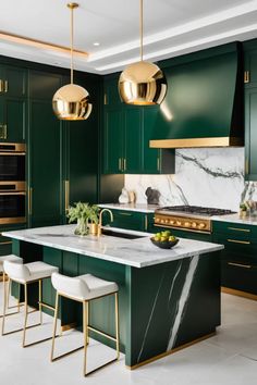 a green kitchen with marble counter tops and gold pendant lights hanging from the ceiling over the island