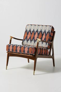 an upholstered chair with wooden legs and arm rests against a white background