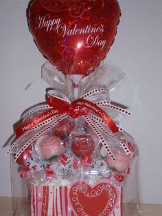 a valentine's day gift box filled with chocolates and candies, wrapped in clear cellophane