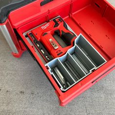 a red toolbox filled with tools on top of a gray carpeted flooring