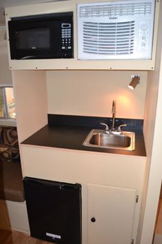 a small kitchen with a sink, microwave and dishwasher on top of it