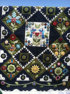 a quilt is hanging on the side of a building with blue sky in the background