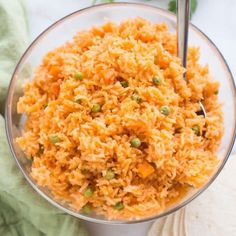 a bowl filled with rice and peas on top of a white cloth next to a napkin