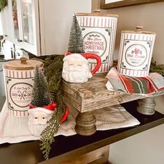 christmas decorations are displayed on a table with santa mugs and other holiday themed items