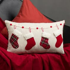 a red and white christmas stocking pillow sitting on top of a bed next to pillows