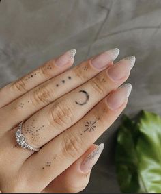 a woman's hand with two rings on it and a crescent moon tattooed on the ring finger