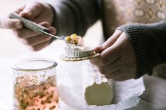 a person is holding a knife and fork over some food on a plate next to a jar