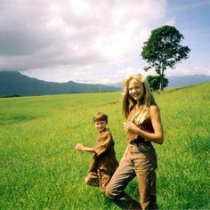 a woman standing next to a boy in a field