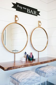 two round mirrors sitting on top of a wooden counter next to stools and a mirror