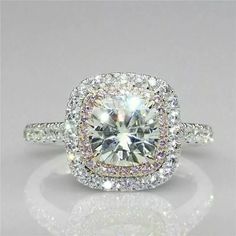 an engagement ring with a large white diamond surrounded by smaller round brilliant cut diamonds in the center