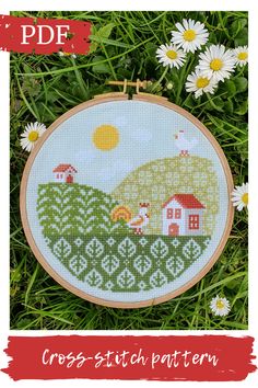 a cross stitch pattern with some daisies in the grass next to it and a red frame