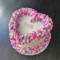 a heart shaped cake decorated with pink and purple flowers