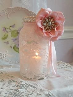 a pink flower sitting on top of a table next to a candle