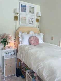 a white bed sitting next to a dresser with drawers and lamps on top of it