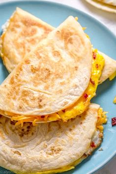 two quesadillas stacked on top of each other on a blue plate next to chips