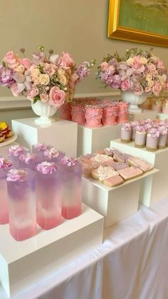 there are many desserts on the table with pink and purple frosted treats in vases