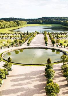 an aerial view of a circular garden with trees and water in the center, surrounded by greenery