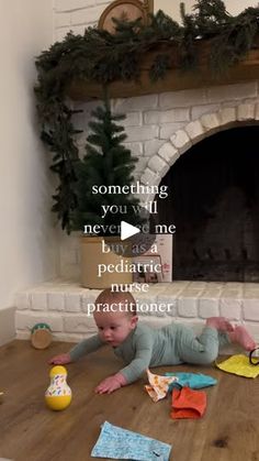 a baby laying on the floor in front of a fireplace