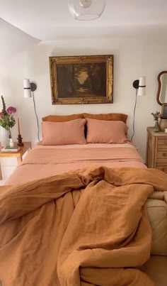 a bedroom with a large bed covered in blankets and pillows next to a painting on the wall