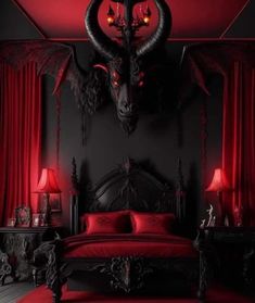 a bed with red sheets and pillows in front of a demon head on the wall