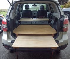 the back end of a van with an open hatchback and wooden trays on it