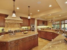 a large kitchen with marble counter tops and wooden cabinets, along with an island in the middle