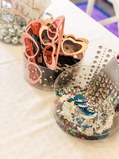 there are many different items in the bowl on the table, including scissors and beads