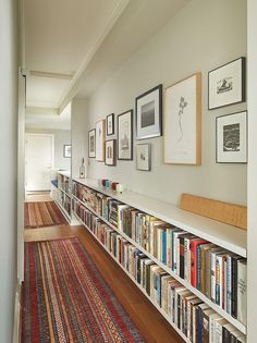 a long bookshelf filled with lots of books on top of a wooden floor