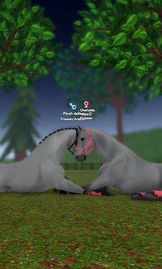 two white horses laying on the ground in front of some trees and grass at night