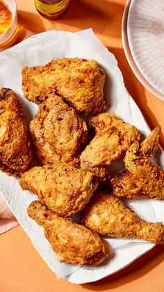 some fried food is on a white plate and next to a glass of orange juice