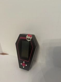 an electronic device with a skull face on it's display case, sitting against a white wall