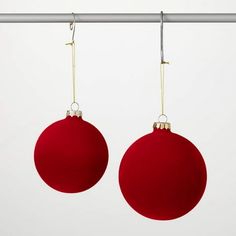 two red ornaments hanging from a metal rod