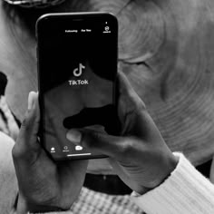 black and white photograph of a person holding an iphone in front of an elephant's head