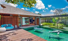 an outdoor swimming pool surrounded by wooden decking and green grass, with two dolphins floating in the water