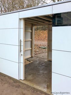 an open garage door on the side of a white building with no doors in it