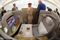 the inside of an airplane with people standing around and eating food on trays in it