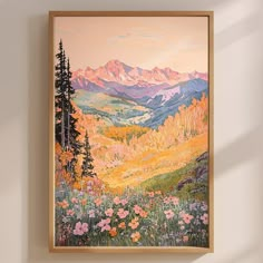 a painting hangs on the wall above a chair in front of a window with mountains and flowers