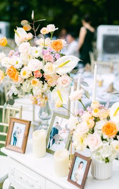 an arrangement of flowers and candles on a table