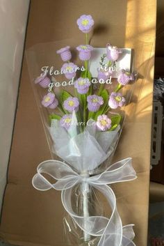 a bouquet of flowers wrapped in cellophane and tied to a box with ribbon