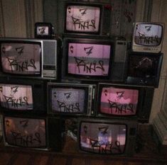 several tvs with graffiti on them stacked up