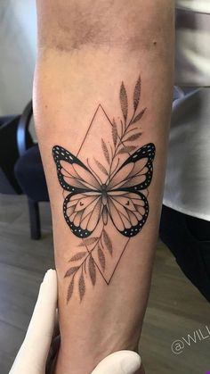 a woman's arm with a black and white butterfly tattoo on the left forearm