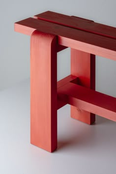 a red wooden bench sitting on top of a white floor