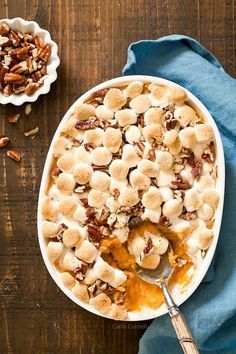 a bowl filled with bananas and nuts on top of a wooden table next to a spoon