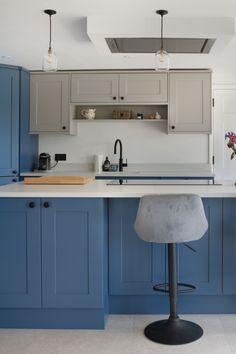 a kitchen with blue cabinets and an island in front of the counter top, has a stool