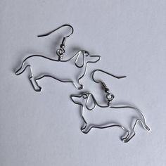 pair of earrings with dog silhouettes on them sitting next to each other in front of a white background