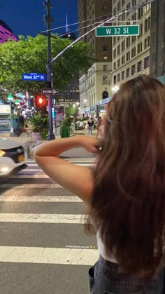 a woman standing on the side of a road next to a traffic light at night