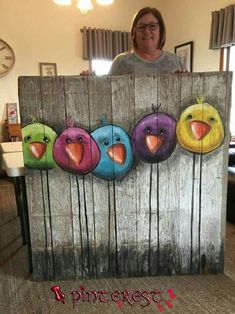 a woman standing behind a wooden sign with birds painted on it